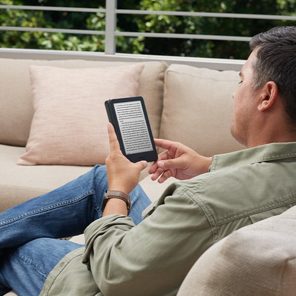 Hombre leyendo relajado en un sofá con su Kindle Basic