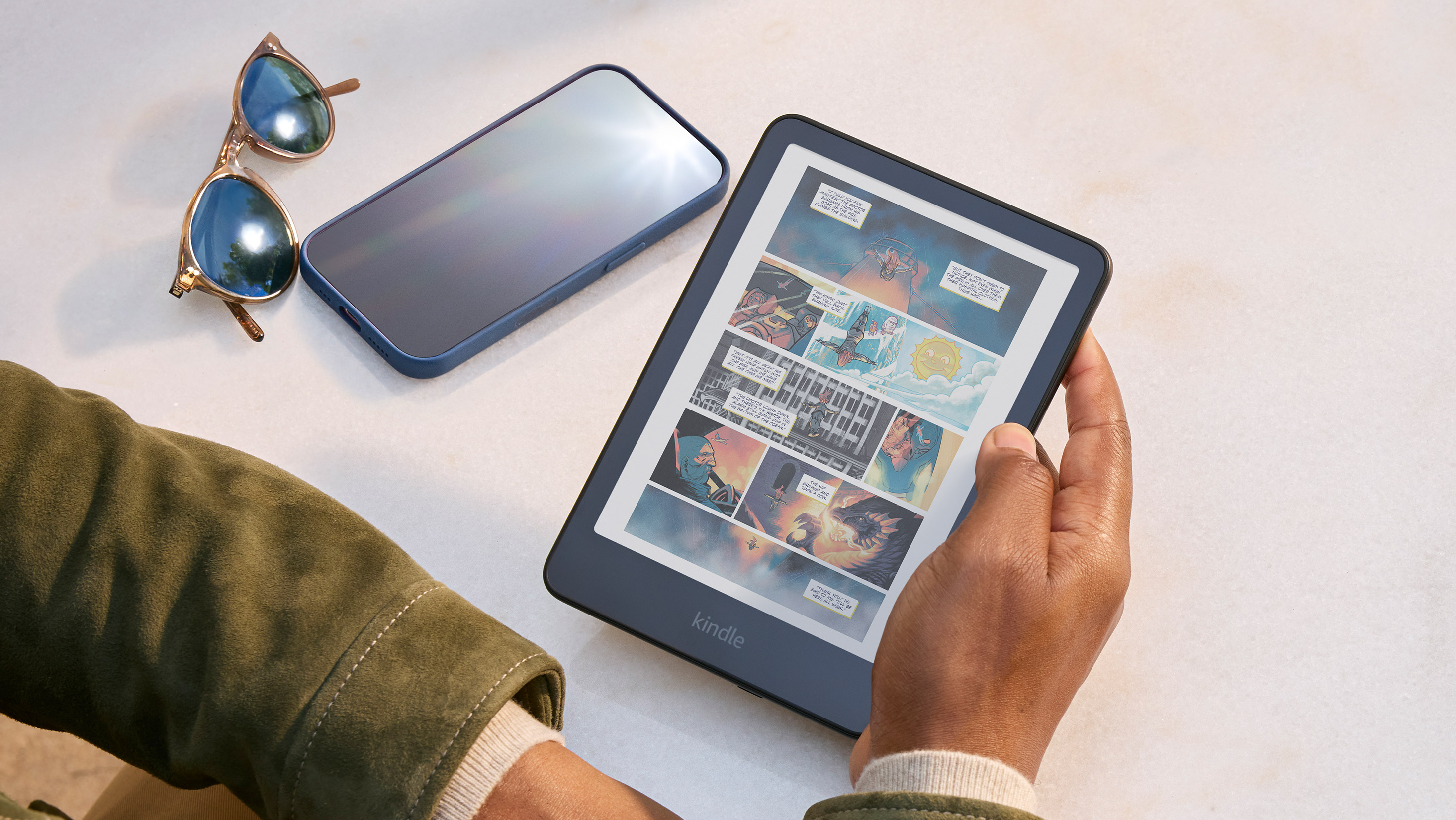 Kindle Colorsoft mostrando un cómic a color junto a un celular lleno de reflejos
