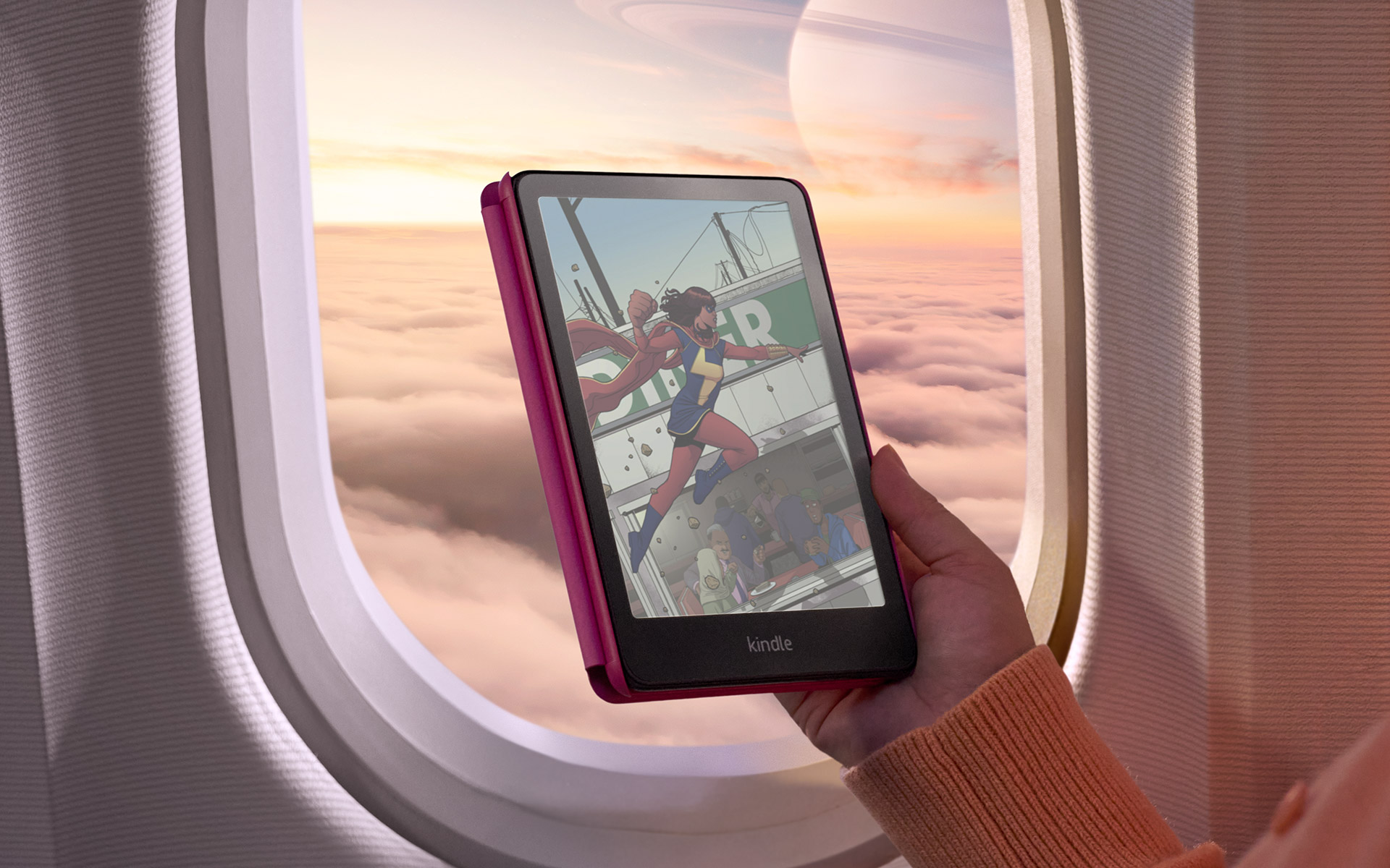 Kindle Colorsoft Signature en funda frambuesa mostrando un cómic a color frente a la ventanilla de un avión